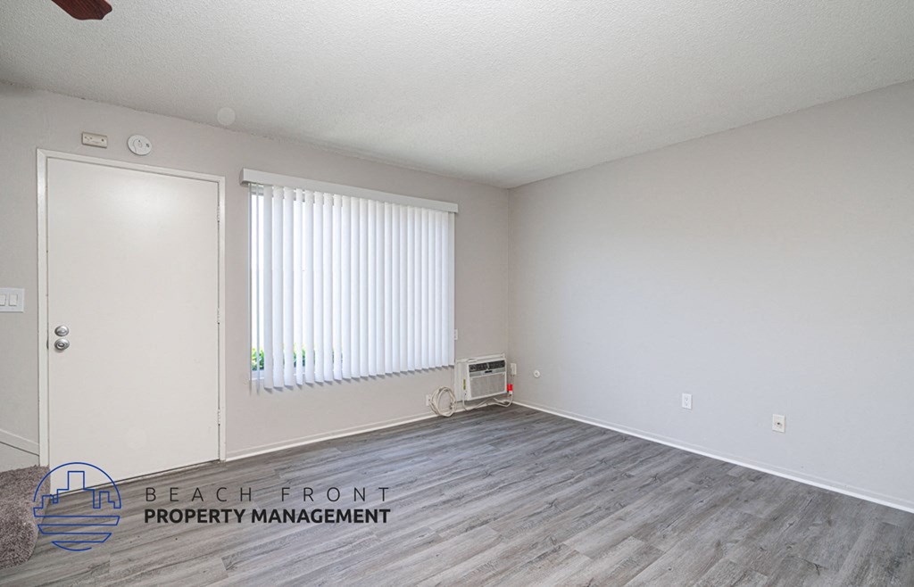 a living room with wood flooring and white walls and a window